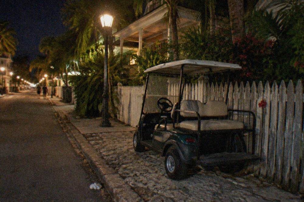 Narrow Old Town lane in Key West at night with bicycles parked against a weathered wooden fence