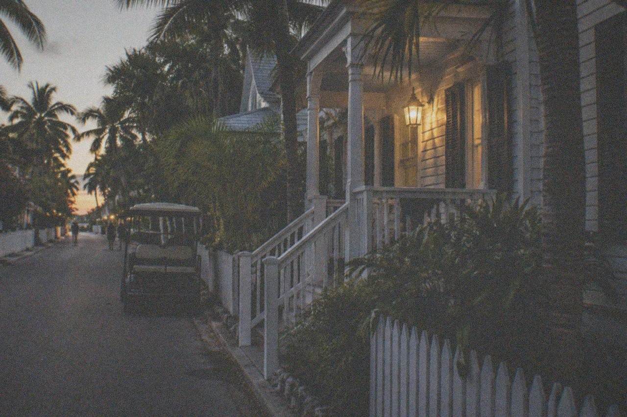 Lantern light on a quiet Key West Old Town street with historic wooden houses at night
