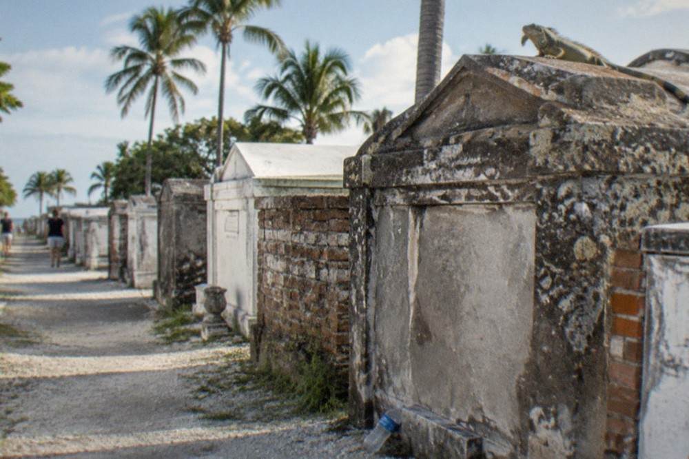 Weathered above-ground gravestones and palm trees inside historic Key West Cemetery