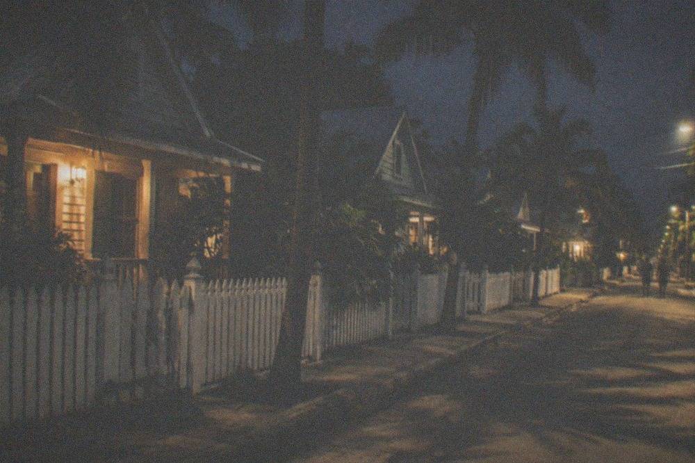 A dimly lit Old Town street with historic conch houses and palm trees