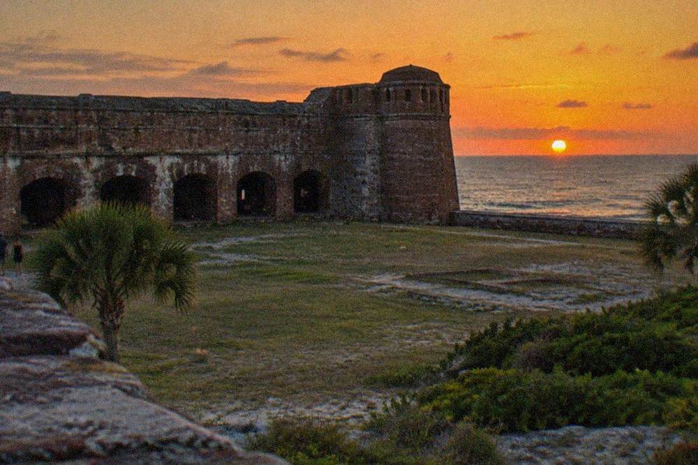A Civil War era brick fort museum with battlements overlooking the water at dusk