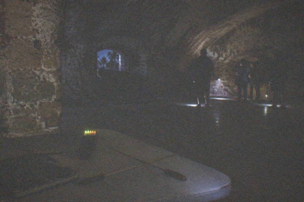 Ghost hunting equipment on a table including an EMF meter and dowsing rods in a dim historic room