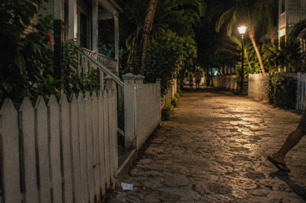 A narrow Old Town lane in Key West at night lit by a single streetlamp beside weathered wooden porches