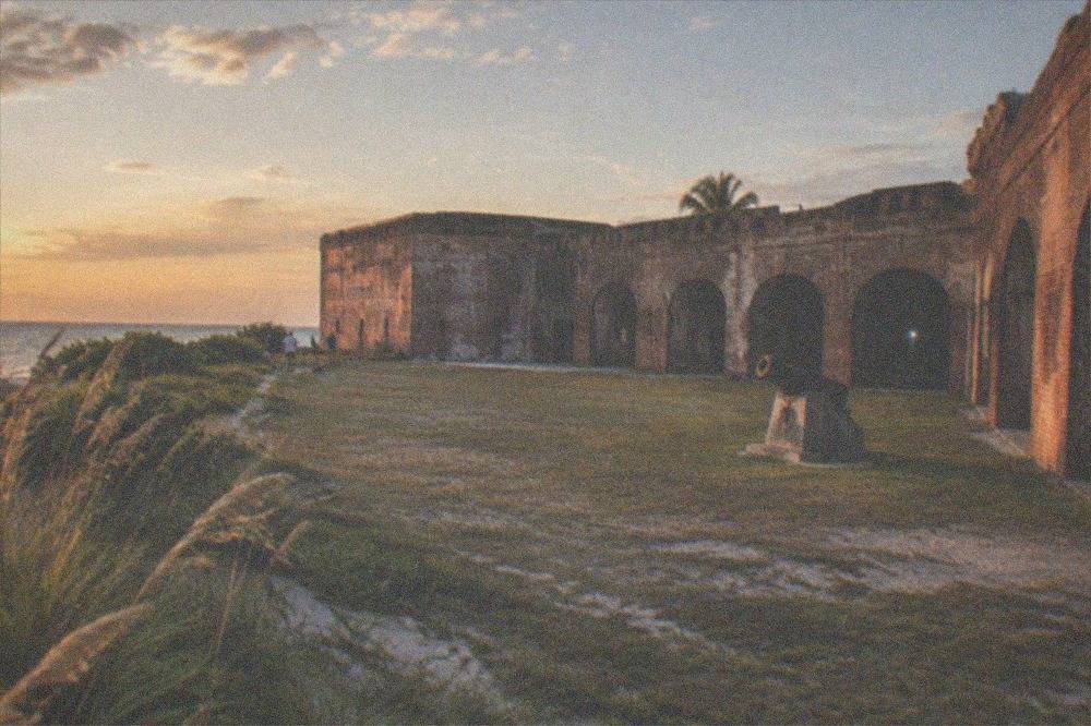 The thick brick walls and open parade ground of Fort East Martello in warm evening light