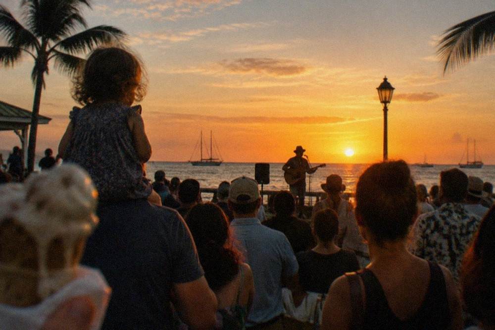 Crowd gathered at Mallory Square watching a street performer during sunset over the water