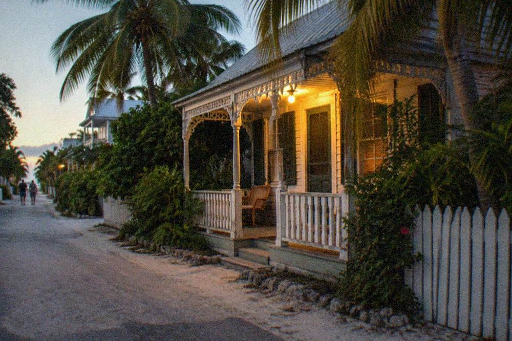 An old wooden Key West building glowing under porch light after dark
