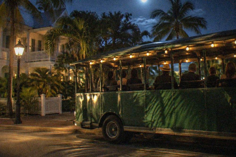 An open-sided trolley parked on a lamplit Key West street at night