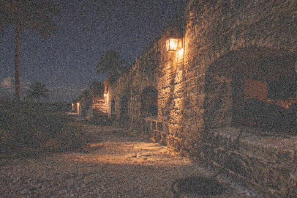 A brick Civil War fort exterior at night with lantern light on the walls