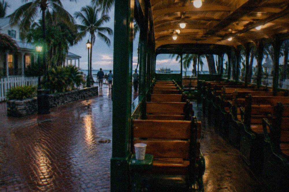 An open-air green trolley parked under lamplight on a quiet Key West street at dusk