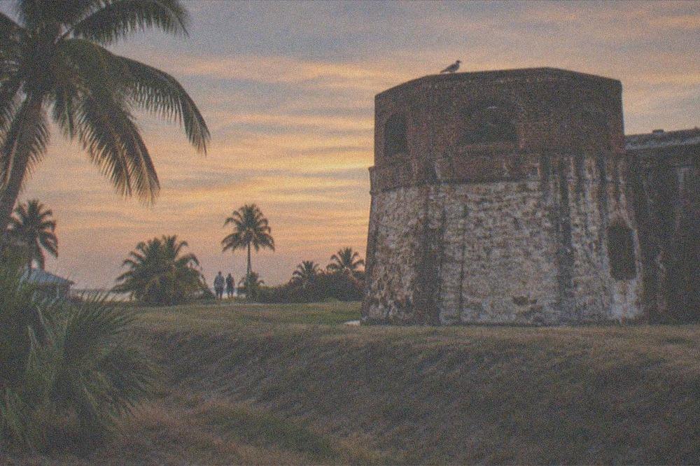 A weathered brick Civil War fort tower standing against an evening sky