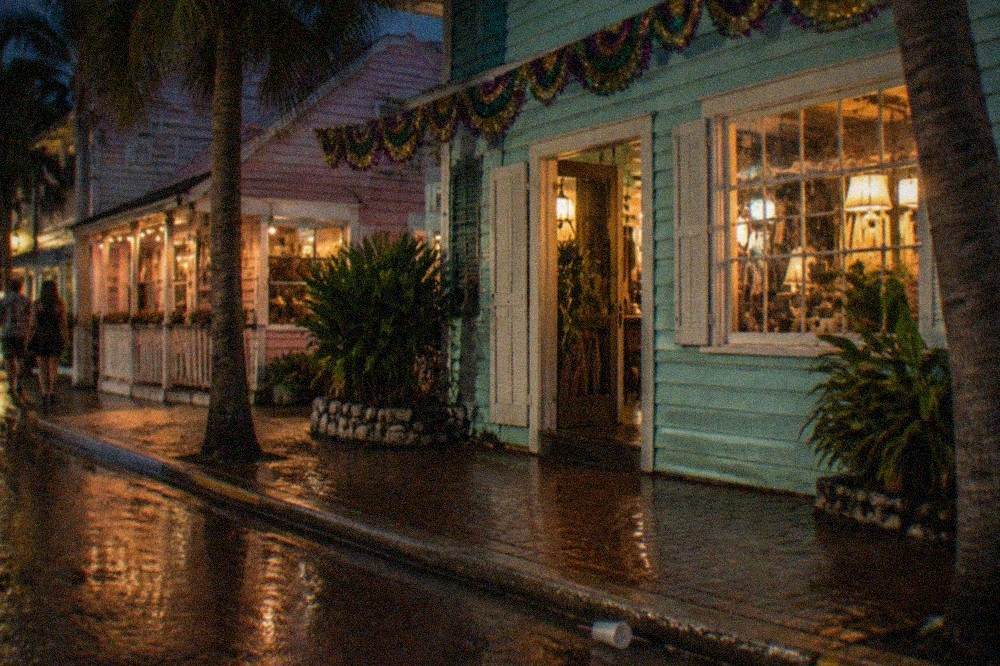 A festive Key West street at night with colorful bunting and illuminated storefronts