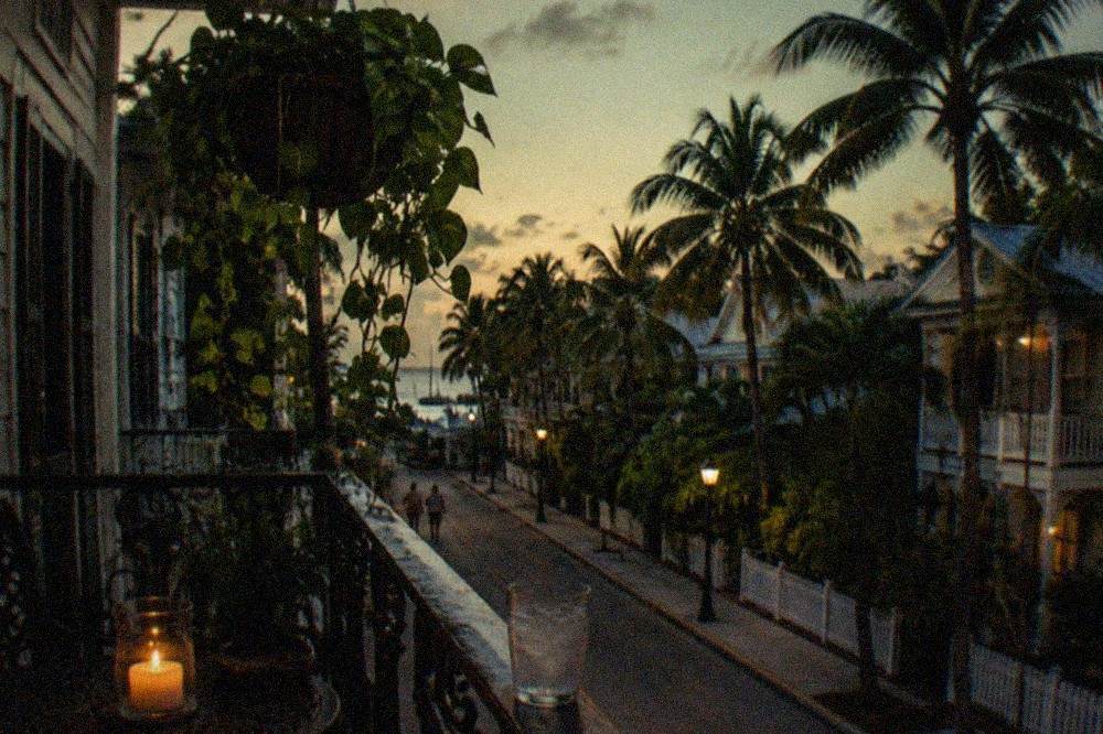 A candlelit historic hotel balcony overlooking a quiet Key West street at dusk