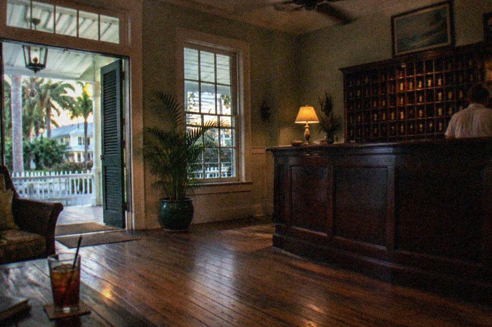 A historic Key West hotel lobby with dark wood furnishings and low evening lighting