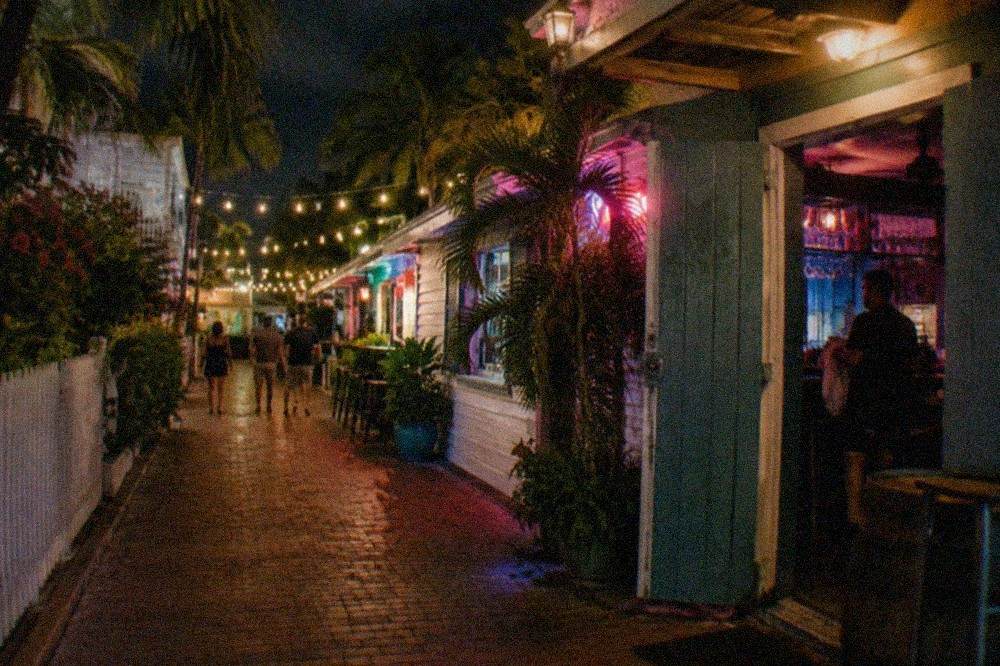Neon signs and string lights above a quiet Key West bar lane at night