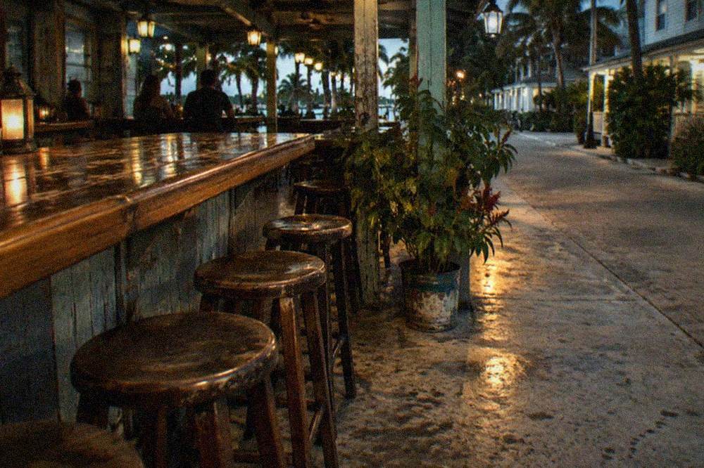 Close view of a covered sidewalk bar counter with stools and lantern light in Old Town Key West