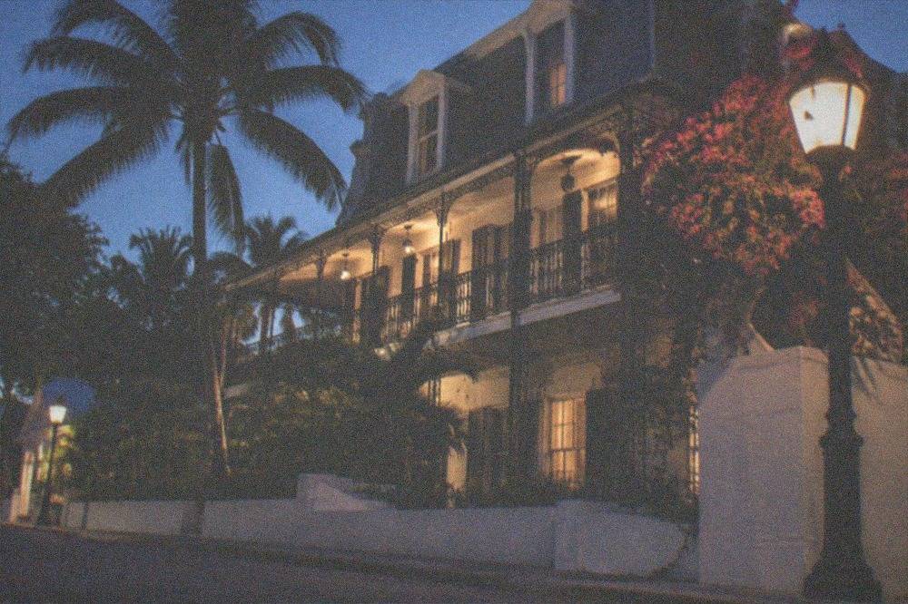 Historic Key West mansion facade lit softly after dark with iron balcony railings