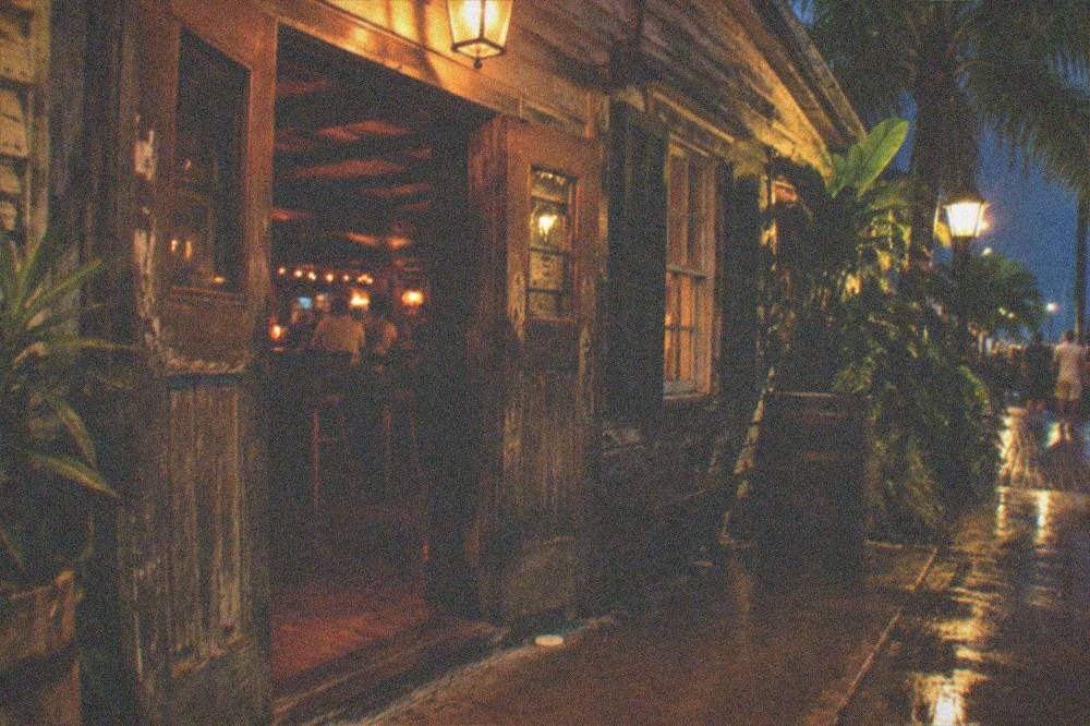 A historic Key West saloon entrance with warm light spilling onto the street at night