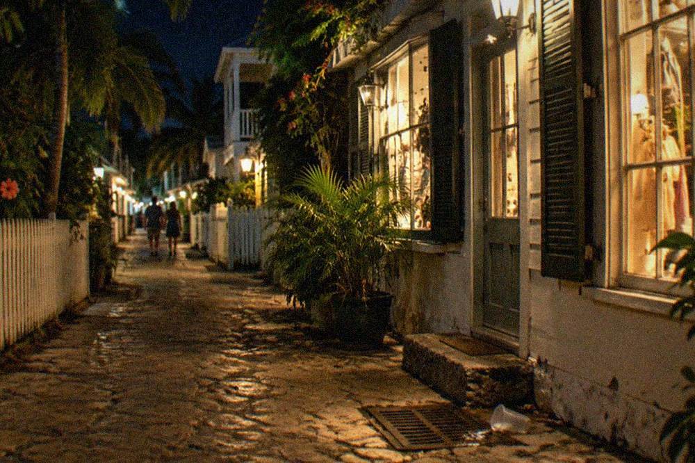 Narrow Old Town lane at night with warm light spilling from storefronts