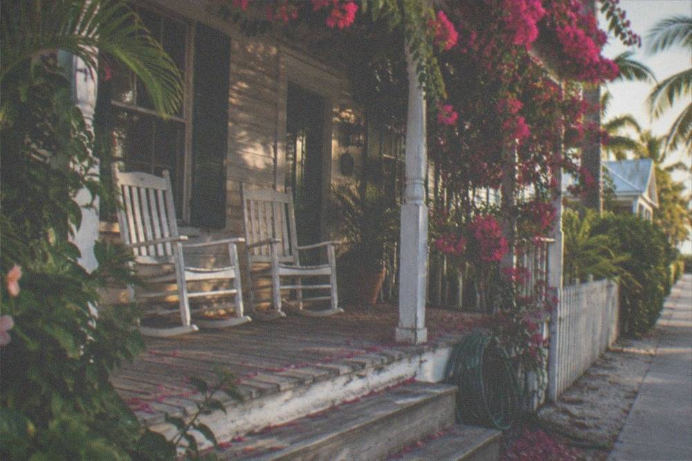 Weathered Key West cottage porch with rocking chairs in late afternoon light
