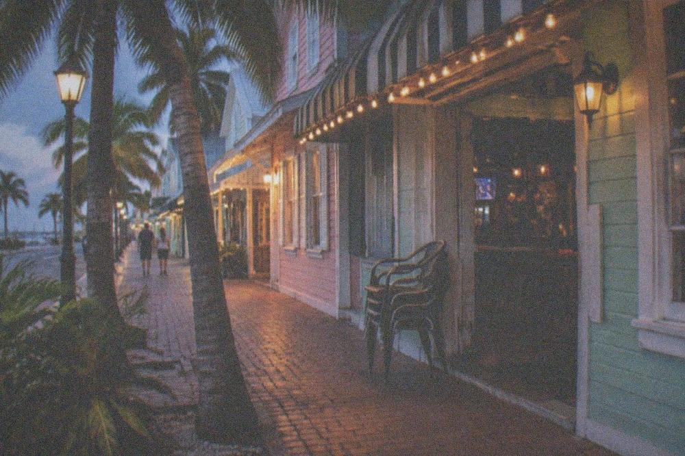 Evening crowd of storefronts along a lamplit Key West street with bicycles parked outside