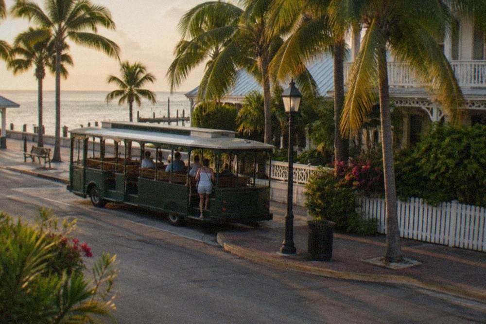 A dark Old Town lane in Key West with white clapboard buildings and a single glowing lantern
