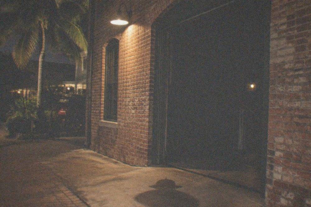 A weathered brick fort wall lit faintly at night with an open doorway into darkness